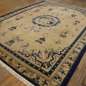 Rectangular tan rug with navy blue medallion and scattered motifs displayed on rustic wood flooring.