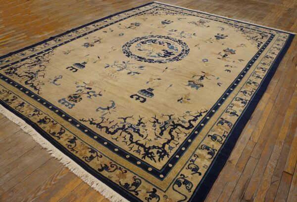 Rectangular tan rug with navy blue medallion and scattered motifs displayed on rustic wood flooring.
