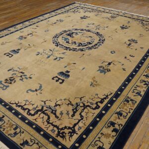 Beige rug featuring a large navy blue medallion and scattered motifs, displayed on distressed wood floors.