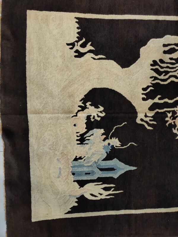 Brown rug corner showing a thick pile cream landscape pattern with light blue elements.