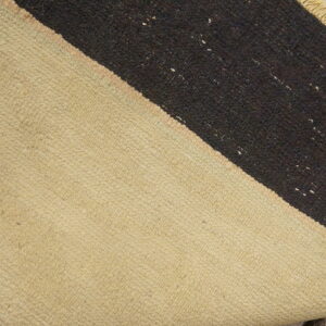 Low-pile rug detail showing natural beige and coarse dark brown diagonal stripes on a wood surface.
