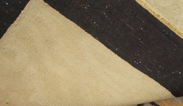 Low-pile rug detail showing natural beige and coarse dark brown diagonal stripes on a wood surface.