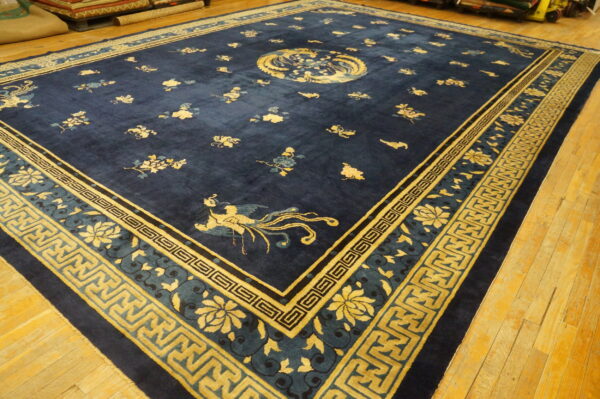 Deep navy blue rug featuring golden yellow stylized floral and geometric border patterns on wood flooring.
