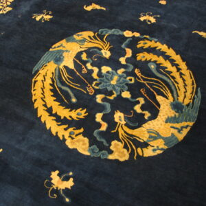 Deep blue rug featuring a gold and teal medallion design of two ornate birds and scattered motifs.