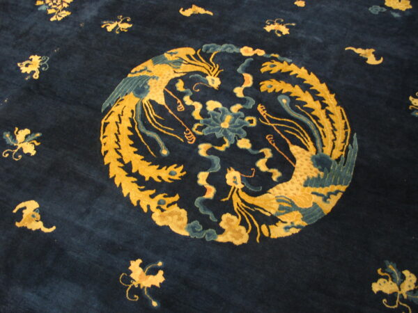 Deep blue rug featuring a gold and teal medallion design of two ornate birds and scattered motifs.