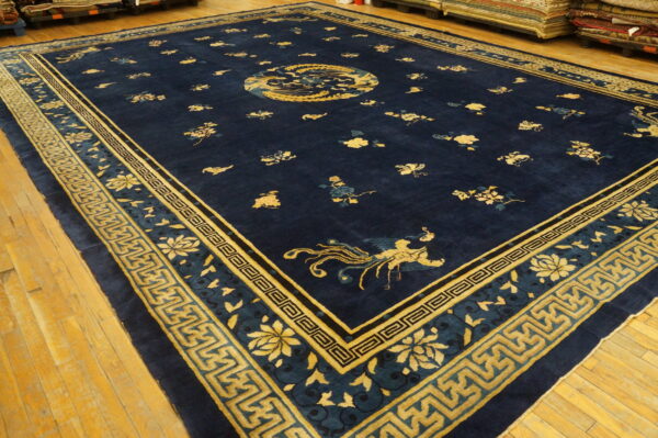 Large navy blue rug featuring gold east asian motifs and geometric fret borders on wood flooring.