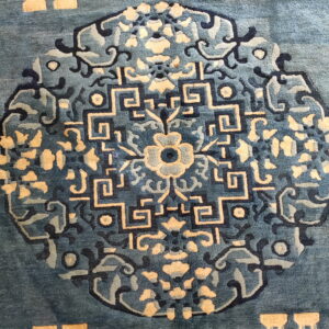 Deep blue rug featuring a complex geometric medallion pattern detailed in cream and navy blue.