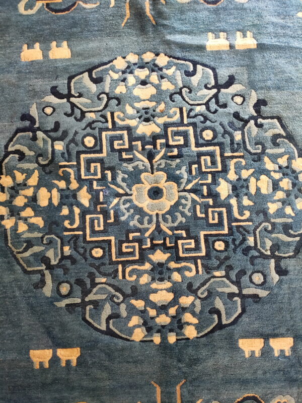Deep blue rug featuring a complex geometric medallion pattern detailed in cream and navy blue.