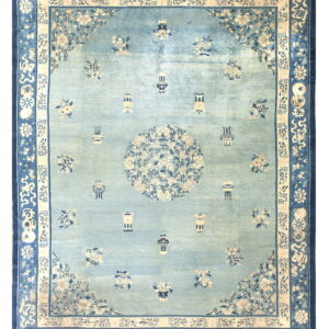 Ornate light blue rug with a central medallion and scattered floral designs within navy and cream borders.