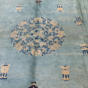 Light blue rug with a plush pile, featuring a central tan and indigo floral medallion and scattered motifs.