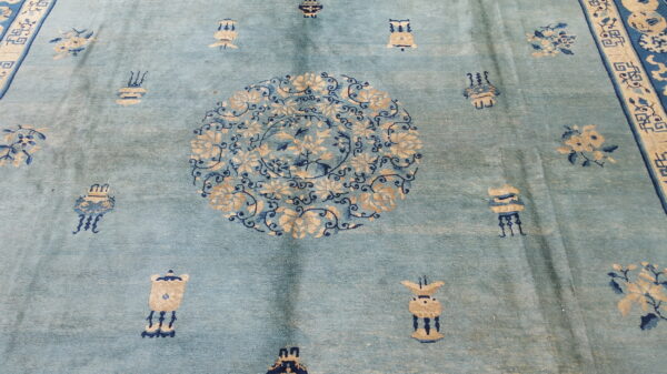 Light blue rug with a plush pile, featuring a central tan and indigo floral medallion and scattered motifs.