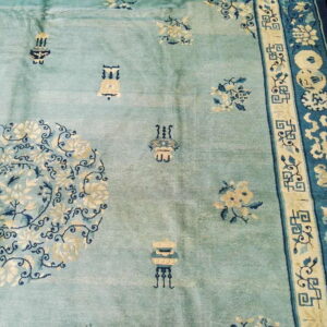 Pale blue rug with cream and navy floral medallions, scattered vases, and detailed geometric borders.