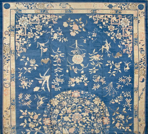 Traditional blue rug featuring detailed cream and pale pink floral and vine designs with geometric borders.