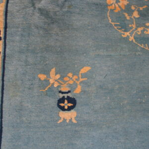Low-pile blue rug featuring distressed texture, a tan and navy vase pattern, and a patterned border.