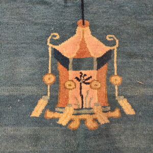 Muted teal rug with a stylized hanging lantern design in salmon, gold, and dark blue.