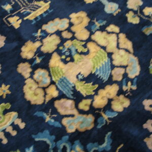 Plush rug detail showing a stylized yellow and green bird pattern on a deep indigo blue field.