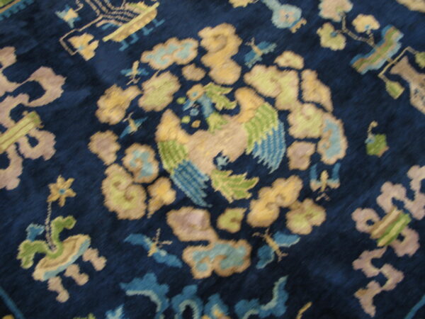 Plush rug detail showing a stylized yellow and green bird pattern on a deep indigo blue field.