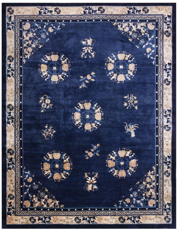 A navy rug featuring scattered beige floral medallions and sprays, bordered by a detailed cream key pattern.