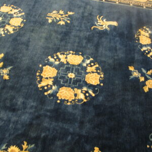 Textured navy rug with gold and light blue stylized floral medallions and scattered foliage designs.