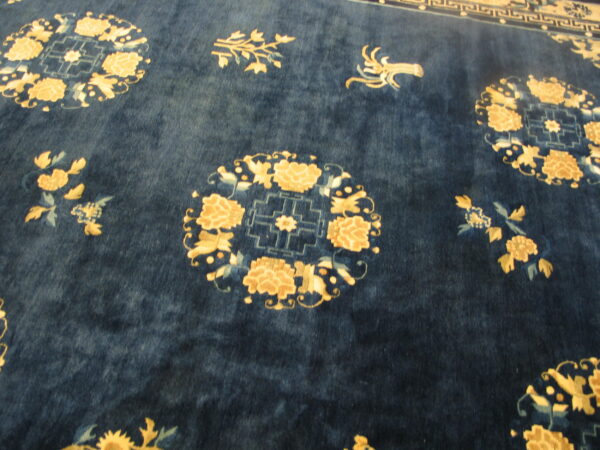 Textured navy rug with gold and light blue stylized floral medallions and scattered foliage designs.