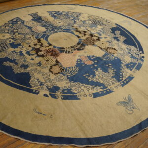 Circular beige rug featuring a detailed blue floral medallion and light pink accents on wood planks.