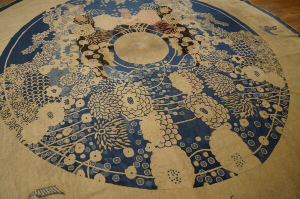 Radial floral rug in deep blue and beige with accents of pink and brown sits on a hardwood floor.