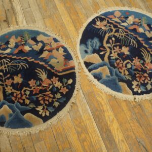 Two round, dark blue rugs with colorful landscape scenes, fringed edges, lying on golden wood planks.