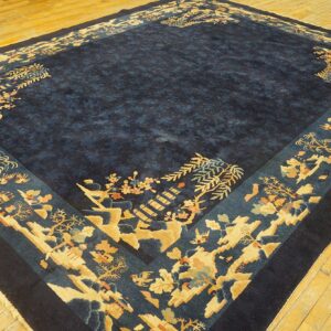 Dark blue rug with a wide border featuring gold and teal landscape motifs on light plank wood flooring.