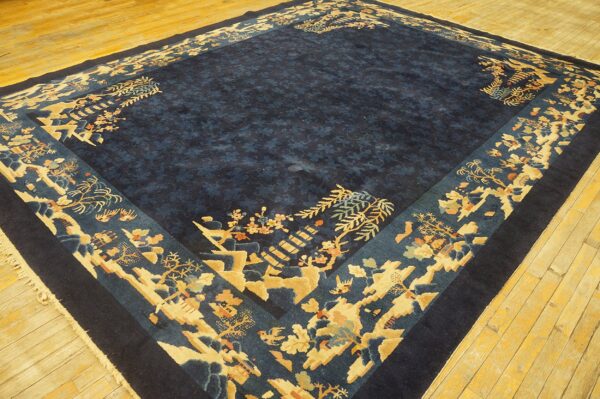 Dark blue rug with a wide border featuring gold and teal landscape motifs on light plank wood flooring.