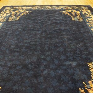 Dark blue rug featuring a subtle floral field and ornate multicolored pagoda and tree borders on wood flooring.