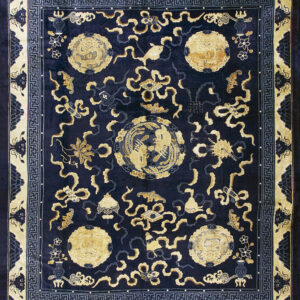 Dark navy rug with gold medallions and scrolling motifs, framed by a complex cream and blue geometric border.