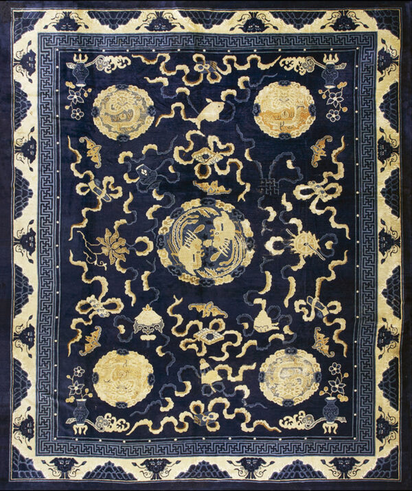 Dark navy rug with gold medallions and scrolling motifs, framed by a complex cream and blue geometric border.