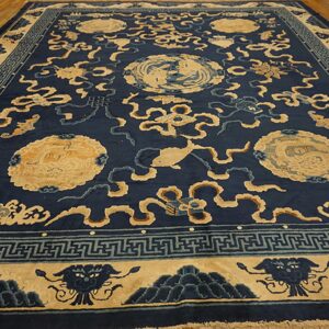 Large navy rug with beige medallions, fish, and stylized clouds resting on light wood flooring.