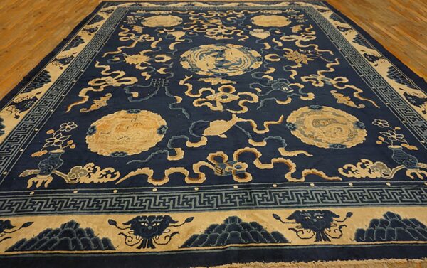 Large navy rug with beige medallions, fish, and stylized clouds resting on light wood flooring.