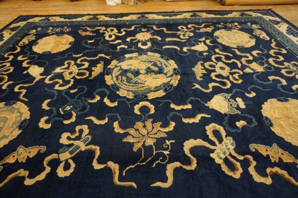 Deep indigo rug featuring intricate gold and light blue ornamental designs is shown on a wooden floor.