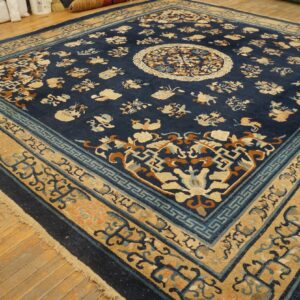 Navy blue rug featuring tan borders and a central medallion rests on worn wooden planks.