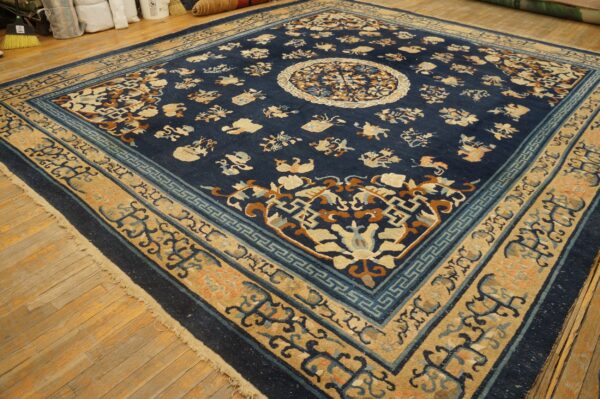 Navy blue rug featuring tan borders and a central medallion rests on worn wooden planks.