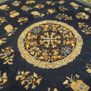 Dark blue rug close-up showing a medallion, scattered gold and rust stylized motifs, and a tan geometric border.