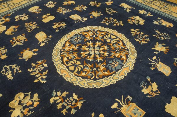 Dark blue rug close-up showing a medallion, scattered gold and rust stylized motifs, and a tan geometric border.