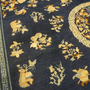 Navy blue rug with scattered gold and rust floral motifs, a partial medallion, and geometric banded borders.