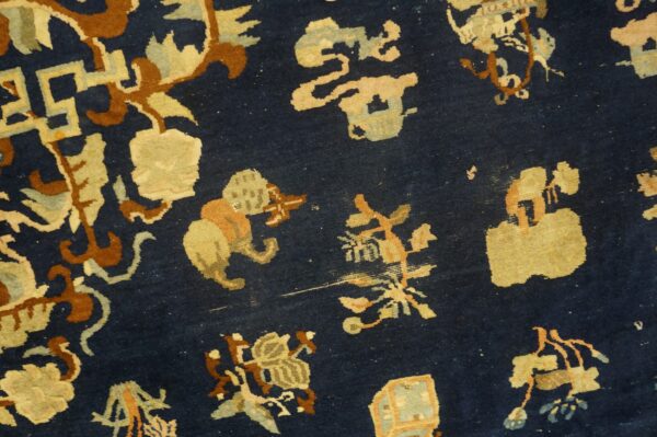 Dark blue rug close-up detailed with stylized shapes in tan, terracotta, and pale blue.