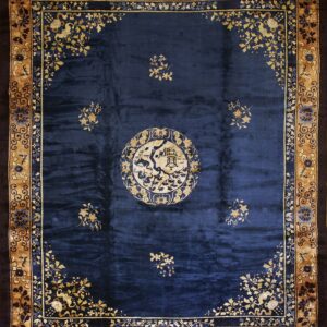 Navy blue rug with a central cream medallion and scattered tan floral designs, framed by an ornate tan border.