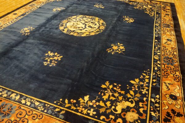 Navy field rug with a gold medallion and rust-colored floral borders on a wood floor.