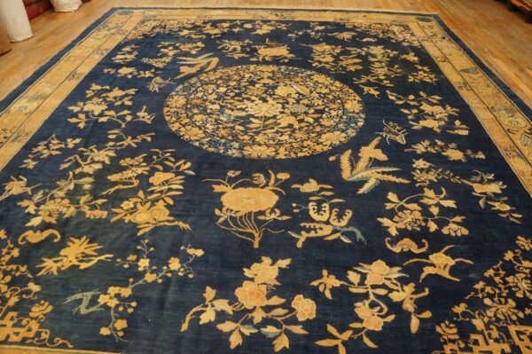 A large navy blue rug featuring golden yellow floral patterns and a central medallion on hardwood floors.