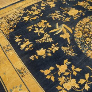 Detailed navy blue rug with contrasting gold floral and bird designs rests on light wood floor.