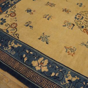 Gold rug with blue floral borders and an oval medallion, set on rustic wooden flooring.