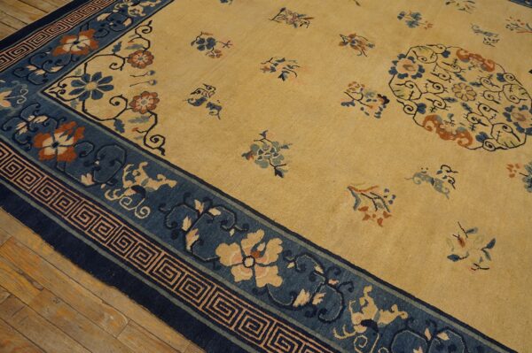 Gold rug with blue floral borders and an oval medallion, set on rustic wooden flooring.