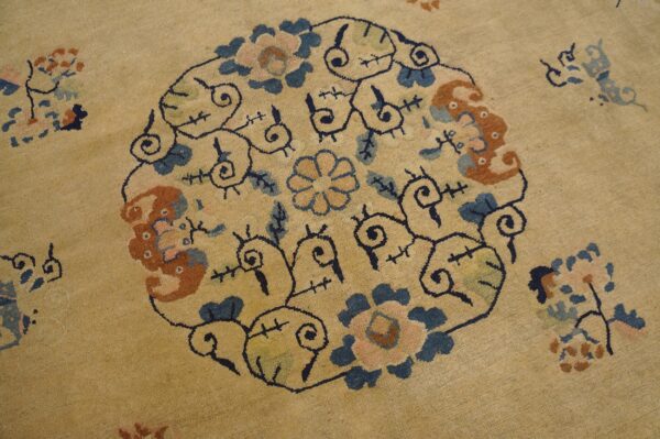 Low-pile tan rug featuring a large circular motif with blue, rust, and rose colored floral designs.