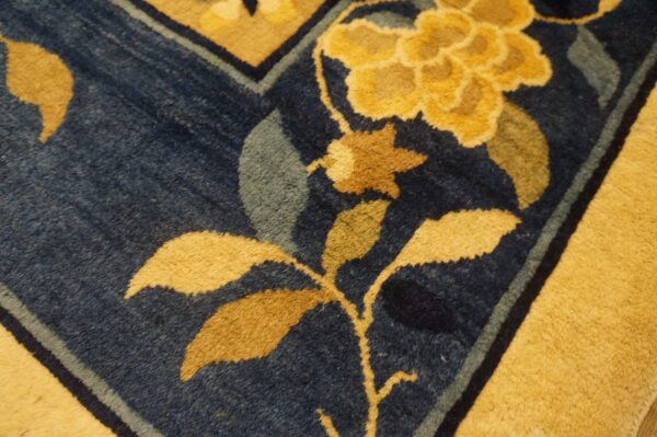 Dark blue rug detail with bold yellow and brown floral elements and a wide gold border.