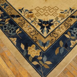 Beige field rug with elaborate blue and gold floral borders, visible on distressed wooden flooring.